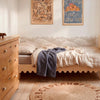 behangrand wolken Dekornik boven bed in kinderkamer met houten meubels