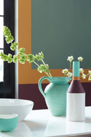 Detailopname van muur geschilderd in Middle Buff 122 met decoratieve accessoires op tafel.