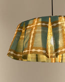 Close-up van brandende geplooide lampenkap in groen en khaki met goudgele gloed