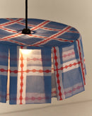 Brandende lampenkap in blauw en rood met zwarte fitting, van dichtbij