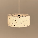 Brandende hanglamp met zwarte stippen tegen een beige muur