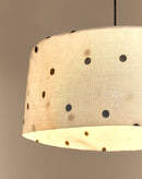Close-up van linnen lampenkap met stippen, aan, met warm licht door de stof