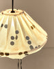Detail van geplooide bovenkant van brandende linnen lampion met zwarte stippen