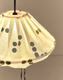Detail van geplooide bovenkant van brandende linnen lampion met zwarte stippen