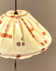 Detail van geplooide bovenkant van brandende linnen lampion met rode stippen