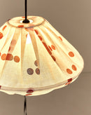 Detail van geplooide bovenkant van brandende linnen lampion met rode stippen