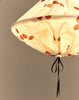 Close-up van onderkant brandende lampion met terracotta stippen en zwart lintje