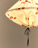Close-up van onderkant brandende lampion met terracotta stippen en zwart lintje